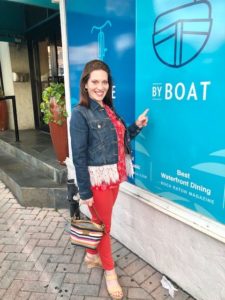 Pamela points to By Boat waterfront restaurant sign in Miami